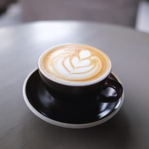 Closeup image of a cup of hot latte coffee with latte art on the table in cafe