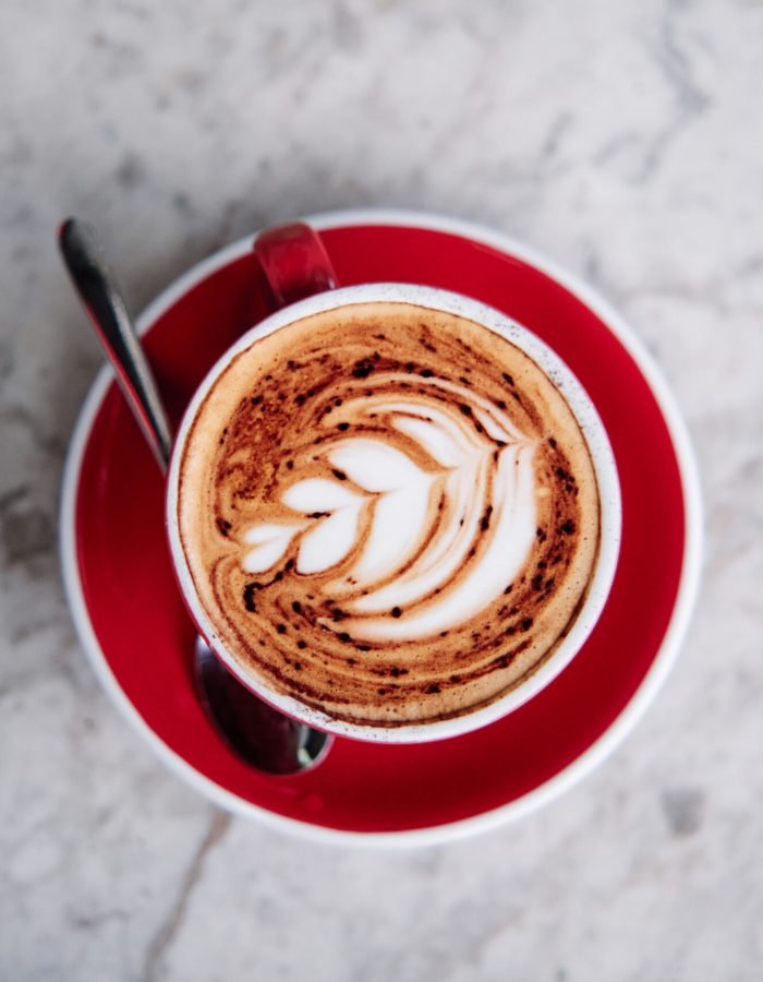 Latter art, rosetta flower on a foamy cappuccino, on a red cup at a cafe.